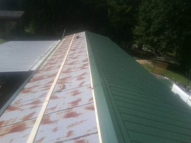 Old rusted panels beside newly installed green metal roofing — Wind Damage Roof Repair by Roofing Brothers in Brookston