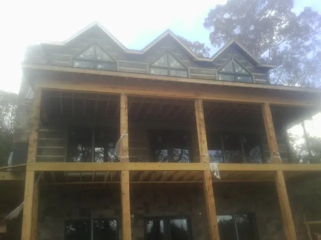Dormers and porch framing on a large log home under construction — Roof Coating work by our crew in Brookston