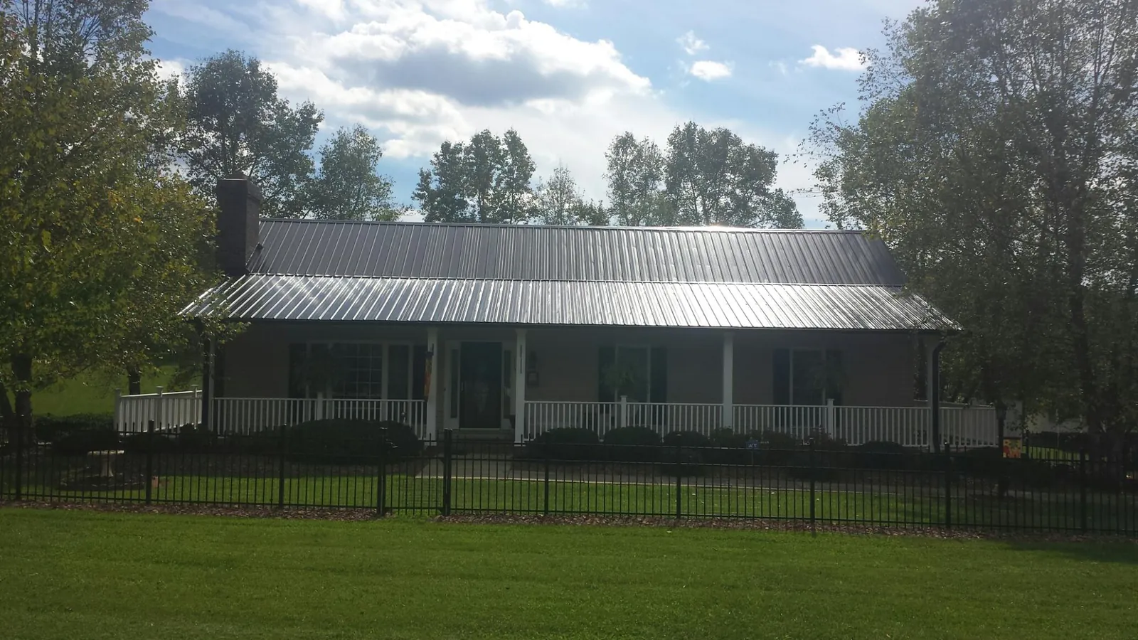 Gray metal roof on a brick ranch with a full width front porch — Gutter Guard Installation work by our crew in Brookston