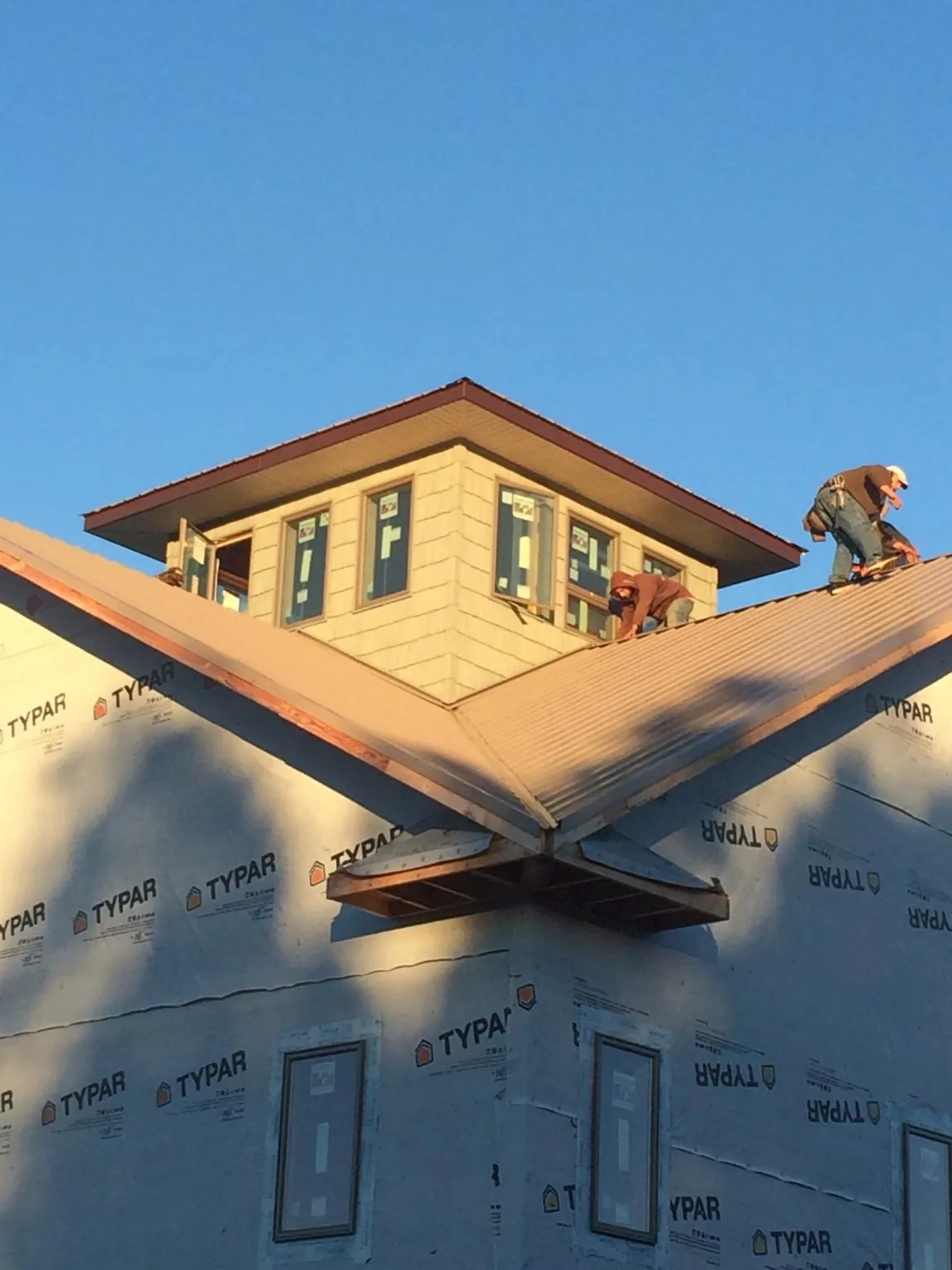 Roofers working around a rooftop cupola on a new metal roof at sunset — Roof Waterproofing in Brookston by Roofing Brothers